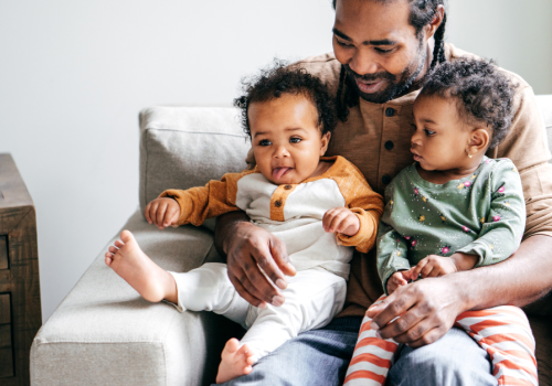 Man sits with his two young children on his lap.